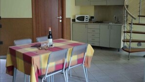 Un comedor con una mesa, sillas, una botella y un microondas al fondo.