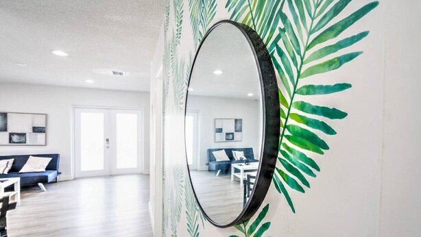 A modern hotel room with a large mirror, a blue sofa, and a dining area.