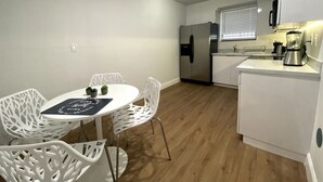 A compact kitchen with white cabinetry, a stainless steel refrigerator, a coffee maker, and a window with blinds. - Renovated 2/1 apt w/ parking near Brickell Center (Miami)