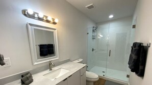 A modern bathroom with a vanity, sink, mirror, and a glass shower enclosure. - Renovated 2/1 apt w/ parking near Brickell Center (Miami)