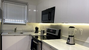 A modern kitchen with white cabinets, a built-in oven, a microwave, a coffee maker, and a blender on the countertop. - Renovated 2/1 apt w/ parking near Brickell Center (Miami)