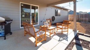 Eine überdachte Terrasse mit Holzmöbeln, einem Grill und Lichterketten.