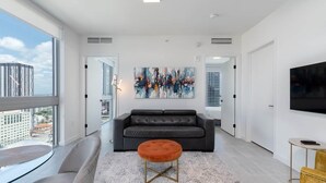 Un salon moderne avec un canapé, un pouf et des œuvres d’art accrochées au mur.