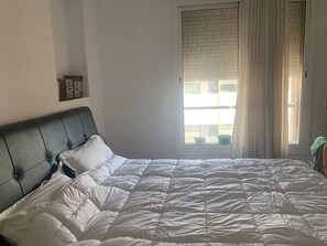 Relax in this serene bedroom with a large bed and a window offering a view of the outside.