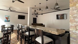 Una cocina moderna con barra, ventiladores de techo y suelo de baldosas.
