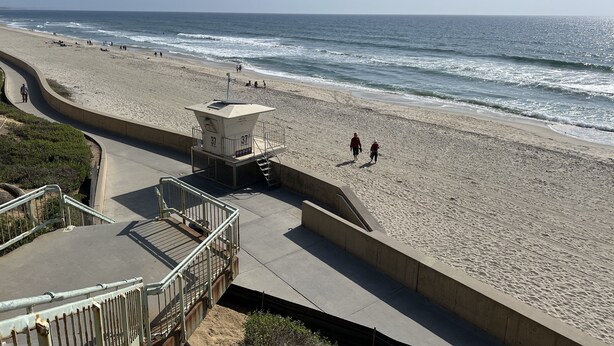 A beach with a lifeguard tower, a curved walkway, and a sandy shore. - Beachside condo #B with 2bd /2 bath (Carlsbad)