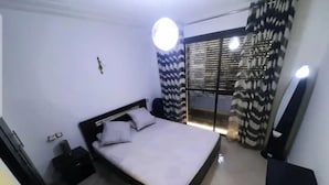 Ein modernes Schlafzimmer mit Bett, Nachttisch, Spiegel und einem Fenster mit Vorhängen.