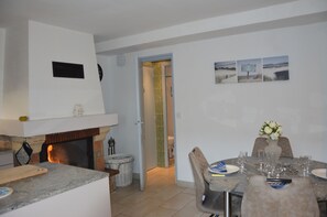 A dining area with a table set for four, a fireplace, and a view of the adjacent room.