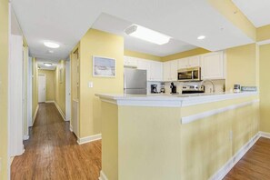 A kitchen with white cabinets, a refrigerator, a microwave, and a coffee maker. - Oceanfront Luxury 4BR Condo w/ Large Balcony & Pool (Myrtle Beach)