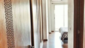 Un pasillo con puertas de madera, un suelo estampado y una cama al fondo.