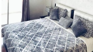 Un dormitorio con cama, ventilador de techo, ventana con cortinas y aire acondicionado de pared.