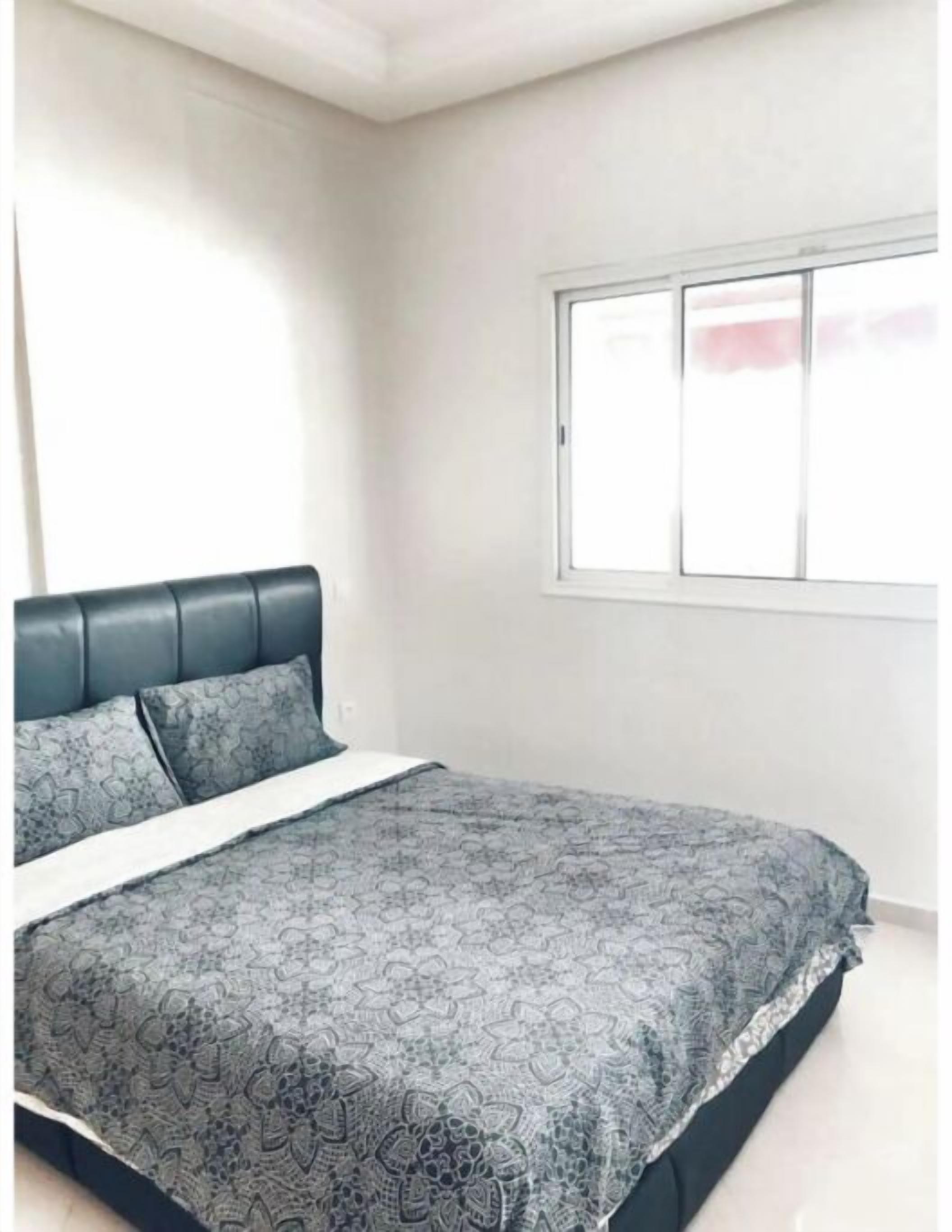 Une chambre à coucher avec un lit, une fenêtre et un mur blanc.
