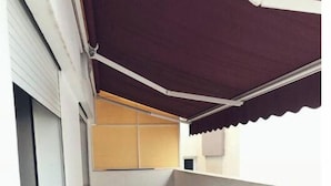 Un pasillo estrecho con suelo de baldosas, una puerta cerrada a la izquierda y un objeto verde pequeño en el suelo.