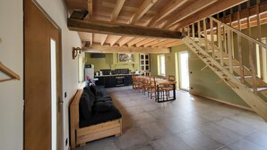 Un vaste espace de vie doté d’un plafond en bois, d’un canapé intégré, d’une table à manger et d’un escalier.