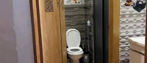 A bathroom with a toilet, a shower, and a sink.