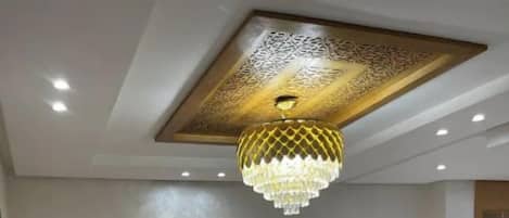 Un salon moderne avec un canapé d’angle, une table basse noire et un luminaire décoratif au plafond.