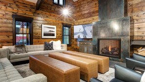 A log cabin interior with a fireplace, a sofa, and a television.