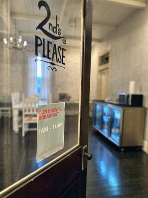 A glass door with a sign indicating Continental Breakfast from 7AM to 11AM.