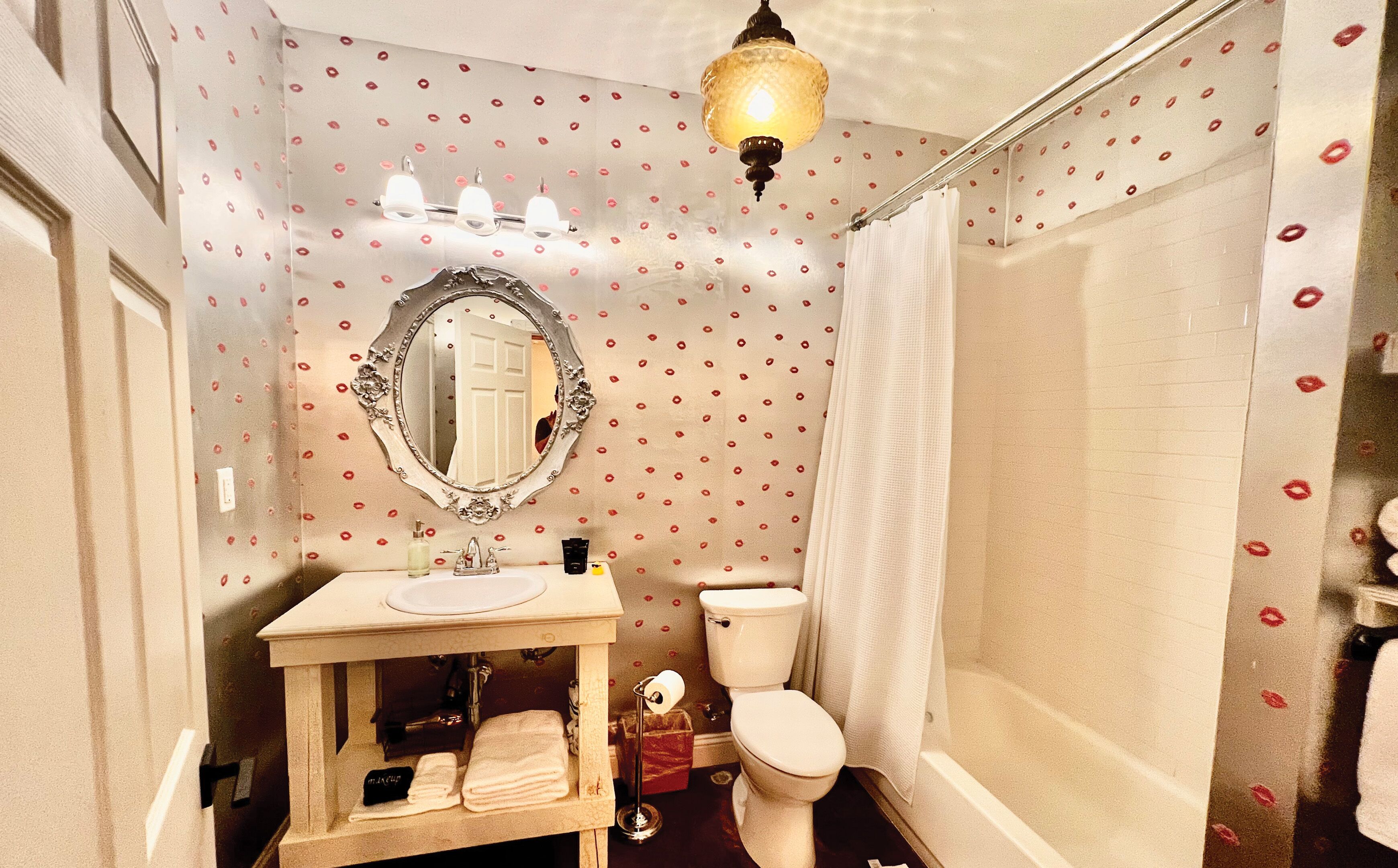 A bathroom with a vanity, sink, mirror, toilet, and shower.