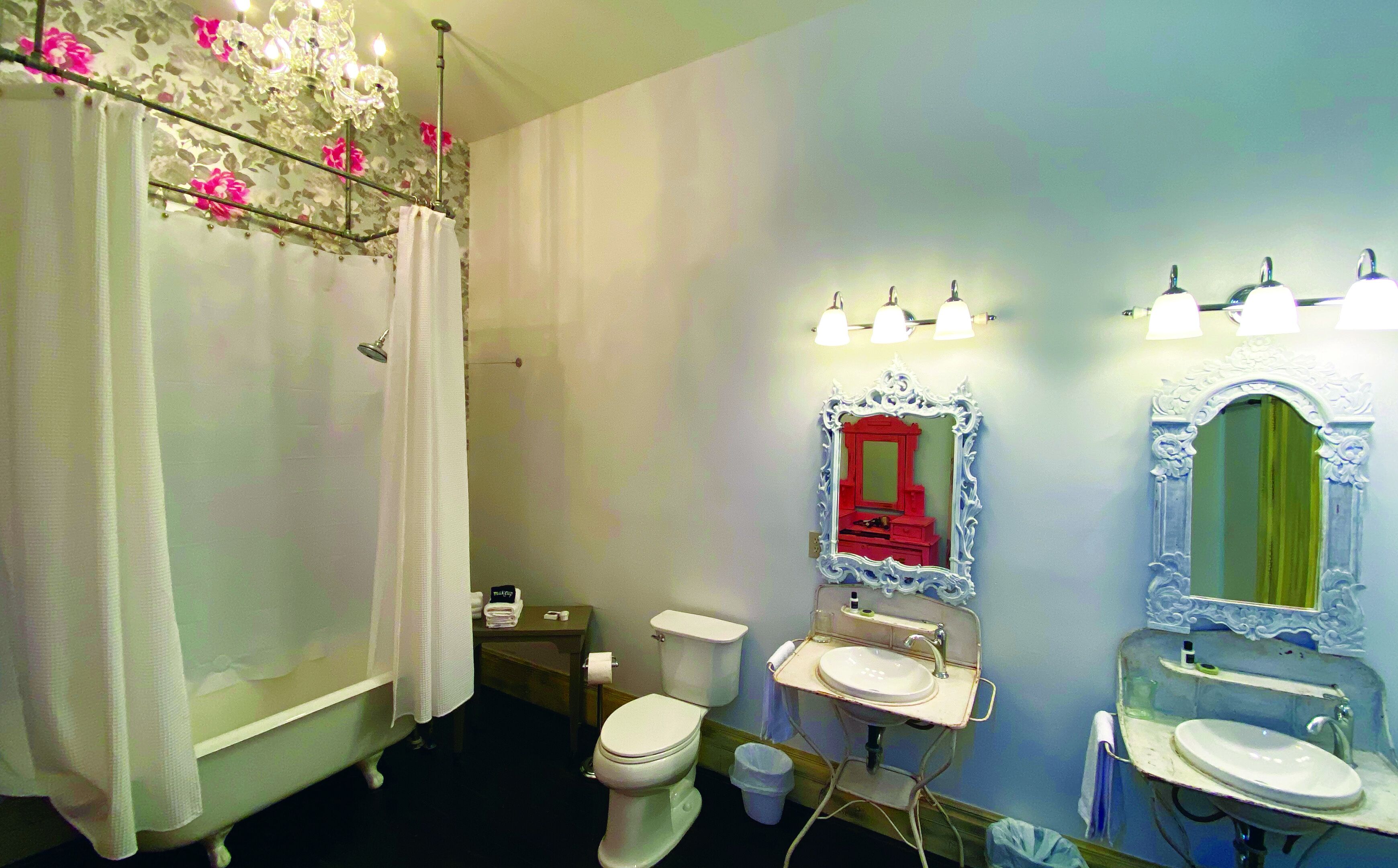 Ein Badezimmer mit Badewanne, Toilette, zwei Waschbecken und einer Duschvorhang.