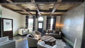 A cozy lounge area with a wooden ceiling, a sofa set, a candelabra, and a wall with a pattern of candles. - MULBERRY (Tishomingo)