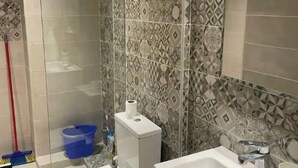 Une salle de bain comprenant des toilettes, un lavabo et un espace douche.