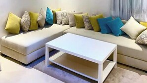 Un salon moderne avec un canapé, une table basse et un luminaire suspendu au plafond.
