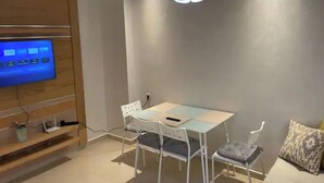 Un espace repas moderne avec une table en verre, des chaises blanches et un luminaire suspendu au plafond.