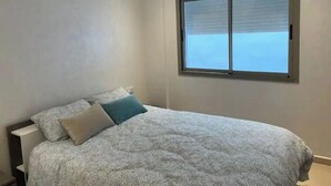 Une chambre à coucher avec un lit, une fenêtre et un luminaire au plafond.