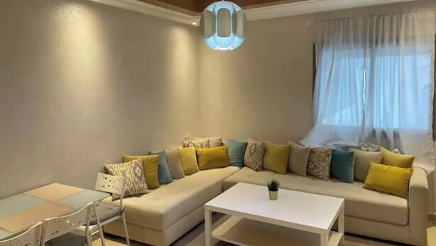 Un salon moderne comprenant un canapé d’angle, une table basse et un coin repas avec une table et des chaises.