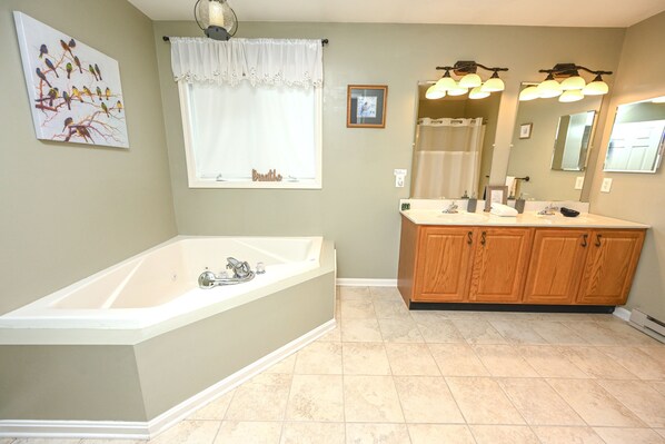A bathroom with a bathtub, wooden vanity, and a large mirror.