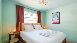 A hotel room with a bed, two bedside tables, a wall-mounted light fixture, and a poster on the wall.