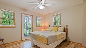 Une chambre à coucher avec un lit, un ventilateur de plafond et des fenêtres équipées de stores.