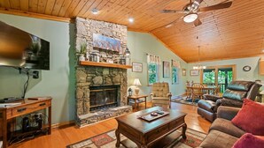 Un salon chaleureux avec une cheminée en pierre, un plafond en bois et des sièges confortables.