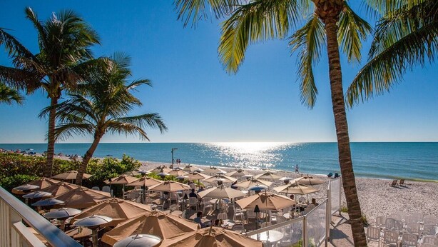 A beachside restaurant with outdoor seating, palm trees, and a view of the ocean. - Beautiful Updated Home, Private Pool, Minutes from Downtown 5th Ave & Beaches!!! (Naples)