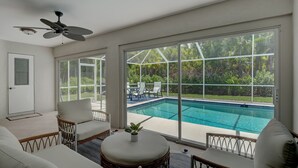 A room with a pool, large windows, and outdoor furniture. - Beautiful Updated Home, Private Pool, Minutes from Downtown 5th Ave & Beaches!!! (Naples)