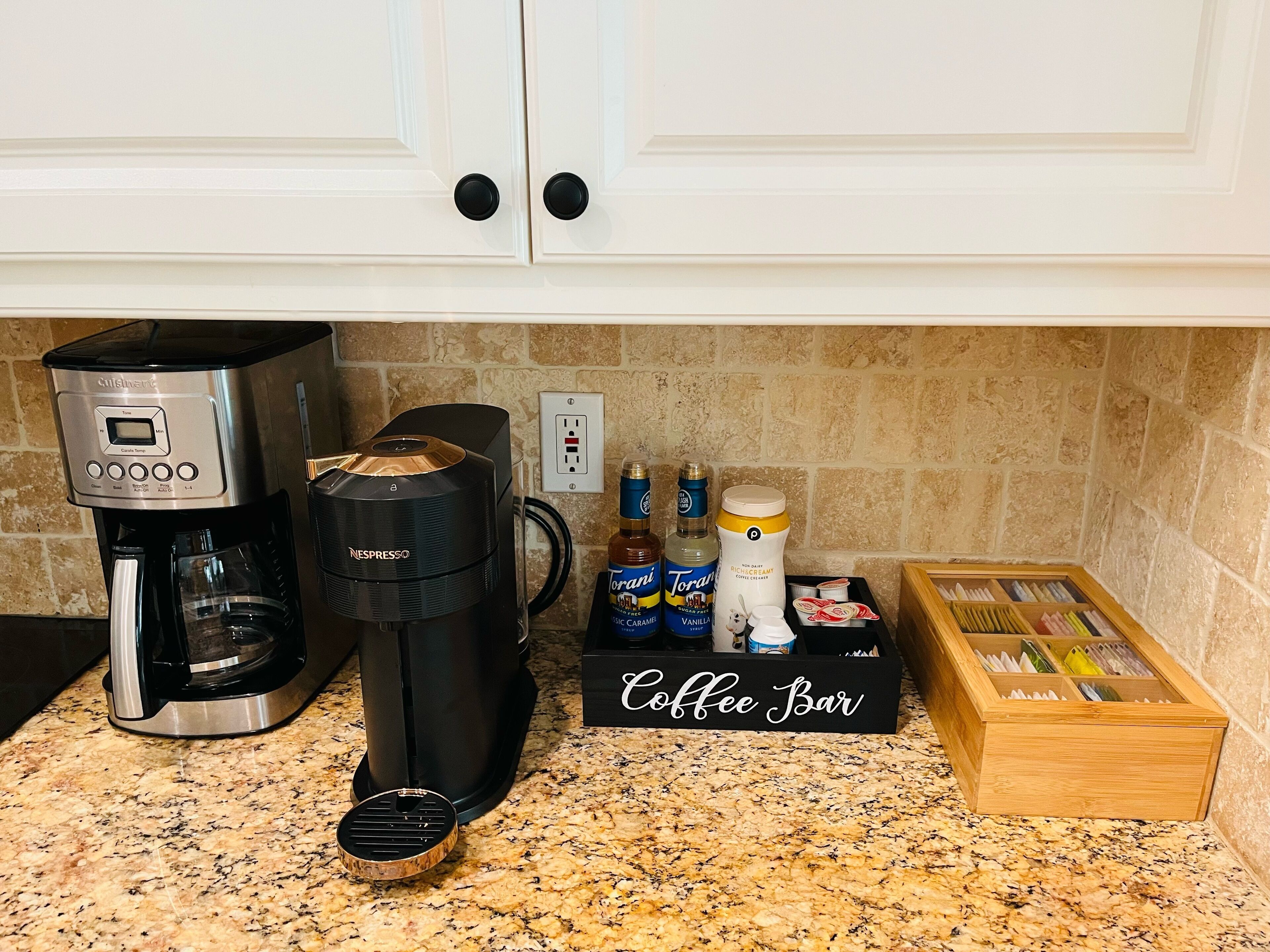 A kitchen with a coffee maker, a Nespresso machine, a coffee bar, and a box of coffee pods.