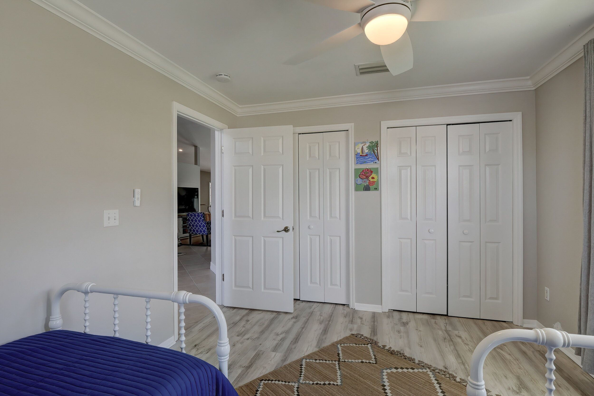 Une chambre à coucher avec un lit, un ventilateur de plafond et un tapis à motifs.