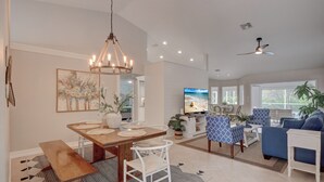 A spacious living room with a dining area, a television, and a ceiling fan. - Beautiful Updated Home, Private Pool, Minutes from Downtown 5th Ave & Beaches!!! (Naples)