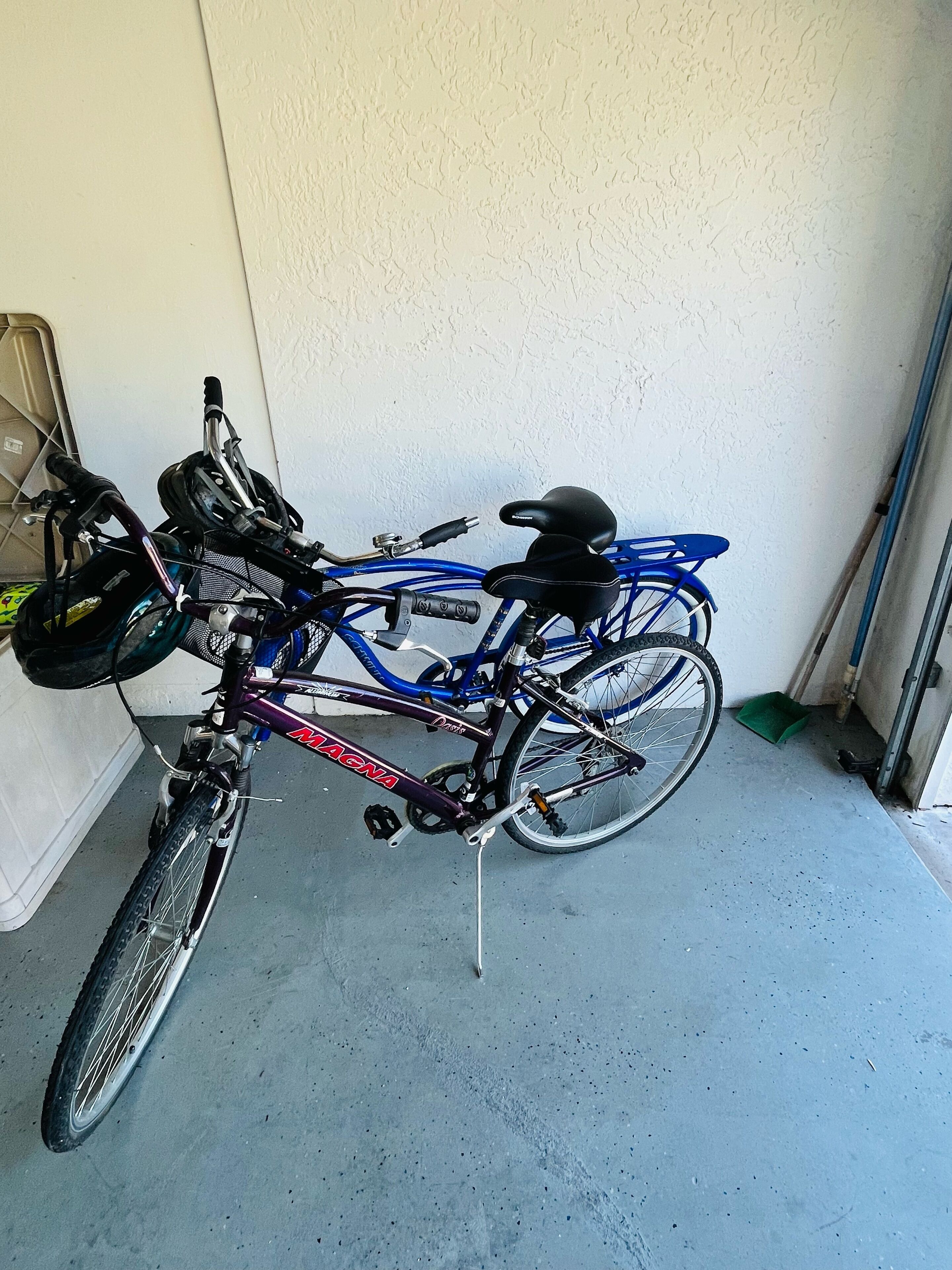 A bicycle with a black seat and a helmet attached to the handlebars, parked against a wall in a garage.