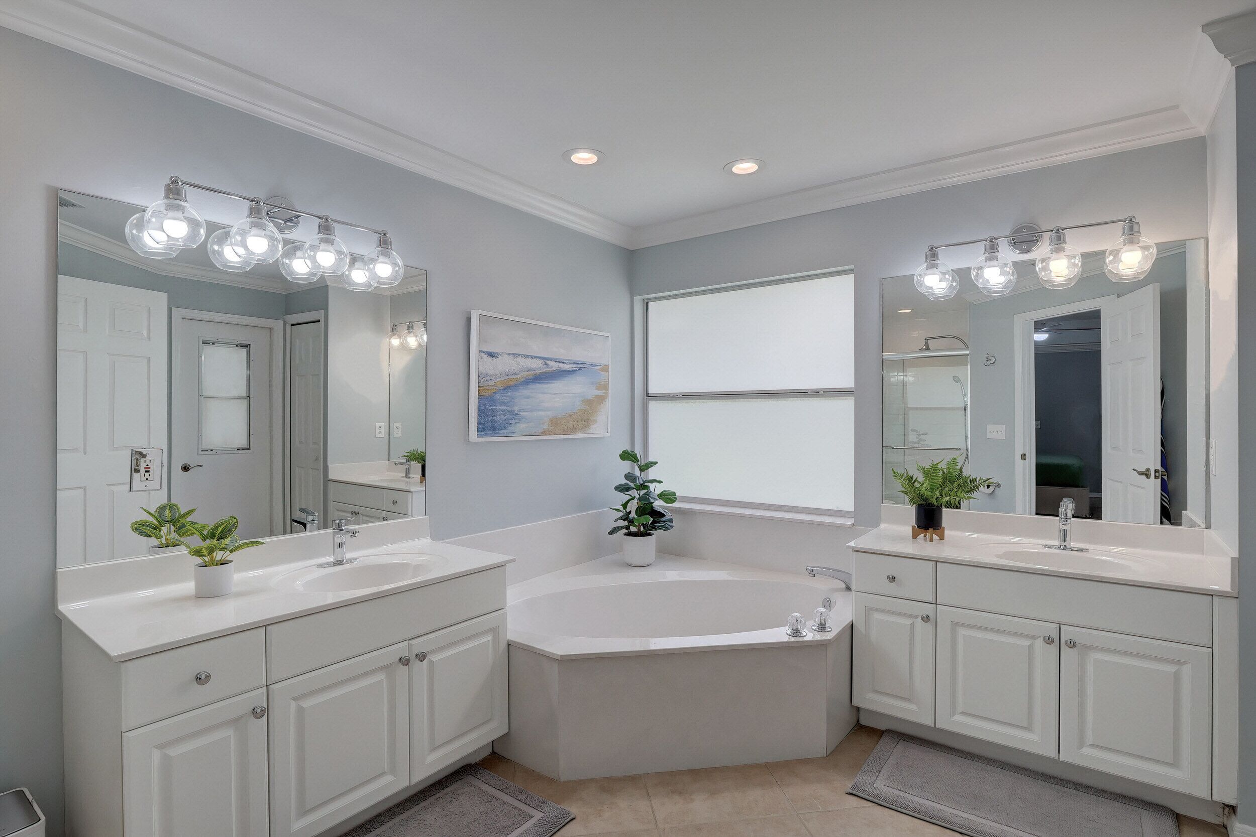 A modern bathroom with two sinks, a large bathtub, and a walk-in shower.