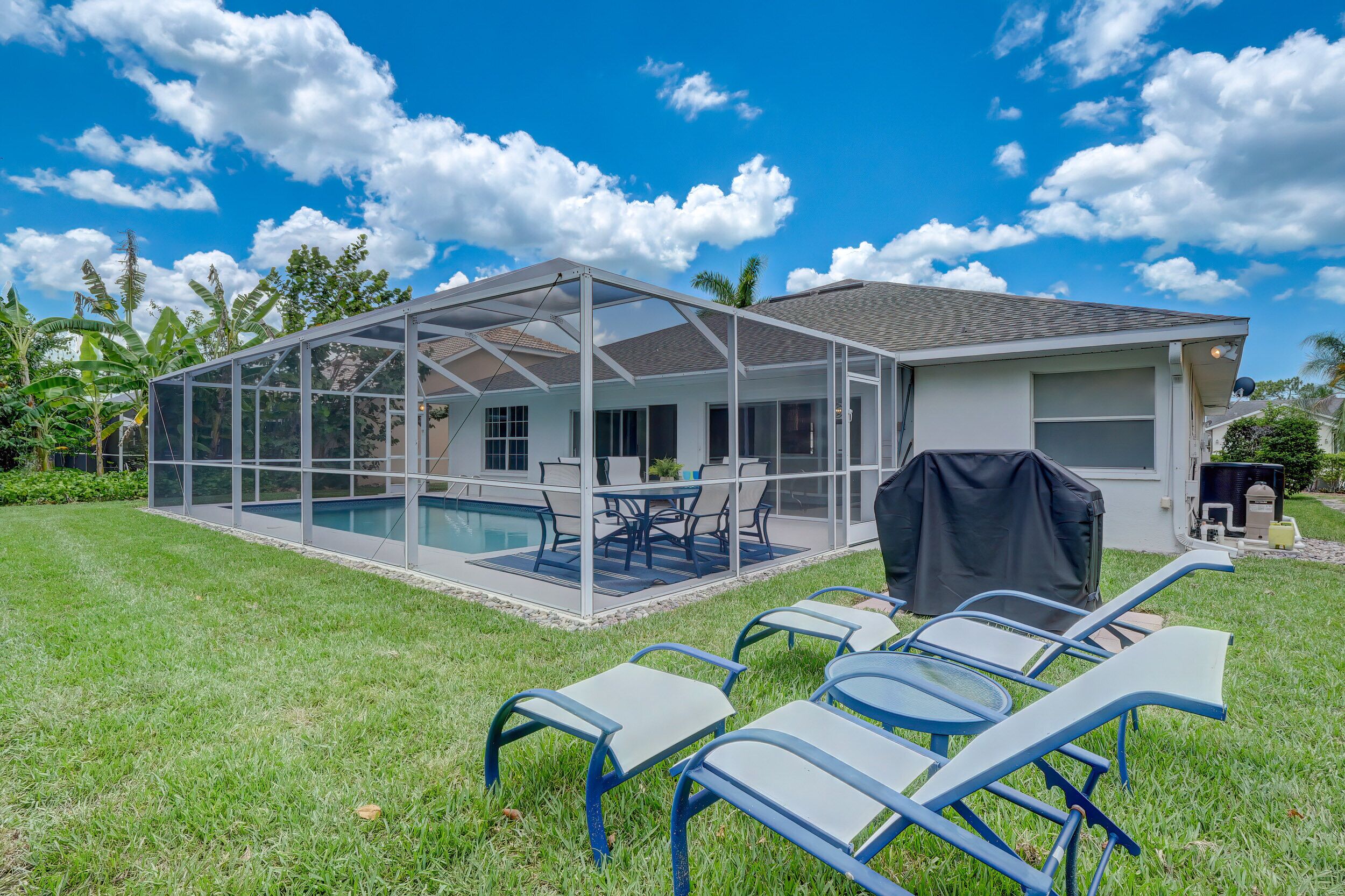A house with a screened porch, a swimming pool, and outdoor furniture.
