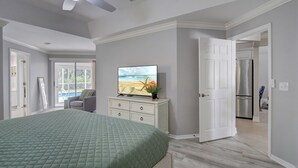 A bedroom with a bed, a television, a dresser, and a door leading to a kitchen. - Beautiful Updated Home, Private Pool, Minutes from Downtown 5th Ave & Beaches!!! (Naples)