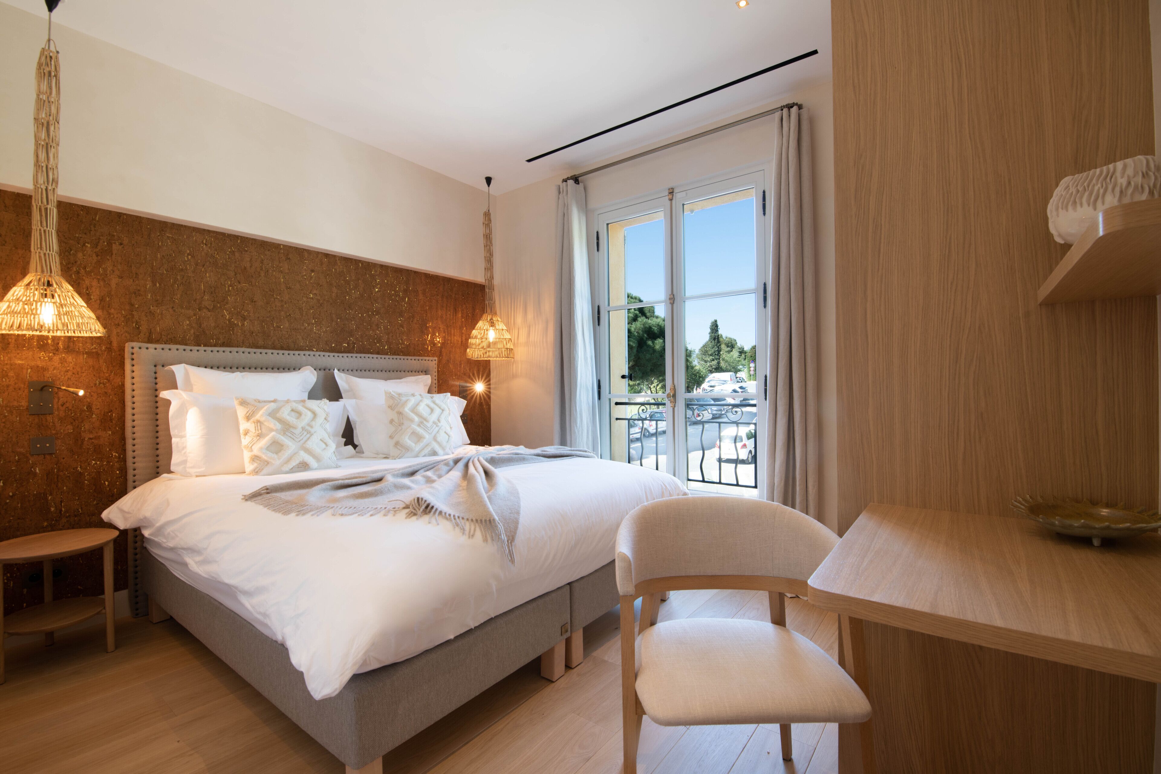 Een moderne slaapkamer met een groot bed, nachtkastjes, een stoel, een bureau en uitzicht op de omgeving.