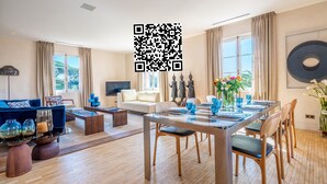 A spacious living room with a sofa, coffee table, and dining area with chairs and a table set for a meal.