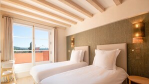 Habitación de hotel con dos camas, un escritorio y vistas al exterior.