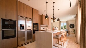 A modern kitchen with stainless steel appliances, wooden cabinets, and a central island with bar stools.