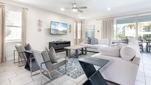 A modern living room with a sofa, coffee table, TV, and a dining area with chairs.