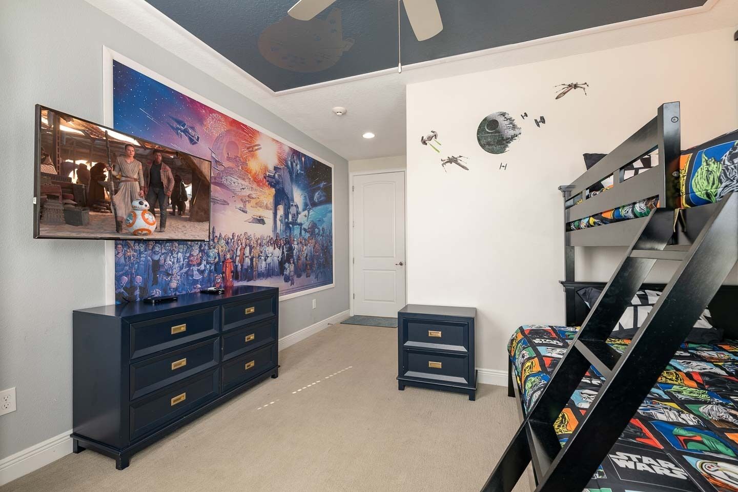 A bedroom with a bunk bed, a dresser, a mirror, and Star Wars-themed decorations.