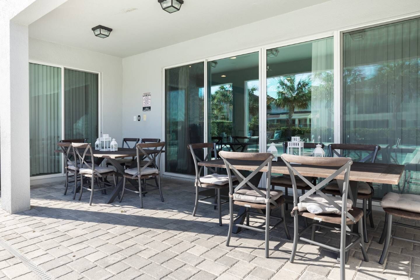 An outdoor patio with a table and chairs, large windows, and a brick floor.